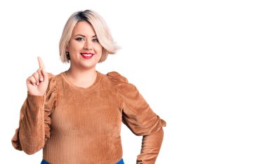 Genç sarışın ve cüsseli bir kadın gündelik süveter giyip bir numarayı gösterirken kendine güvenen ve mutlu gülümseyen.. 