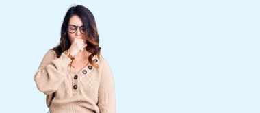 Güzel, genç, esmer, günlük kıyafetler ve gözlük takan bir kadın kendini iyi hissetmiyor ve soğuk algınlığı veya bronşitin belirtisi olarak öksürüyor. sağlık hizmeti kavramı. 