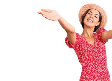 Yaz şapkası takan genç ve güzel bir kadın kameraya bakıp sarılmak için kollarını açmış gülümsüyor. Mutluluğu kucaklayan neşeli bir ifade.. 