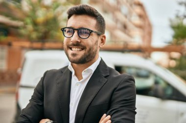 Kollarını kavuşturmuş genç İspanyol işadamı şehirde mutlu bir şekilde gülümsüyor..