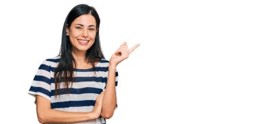 Güzel, genç bir kadın, günlük giysiler içinde, yüzünde kocaman bir gülümsemeyle, eli ve parmağı kameraya bakıyor.. 