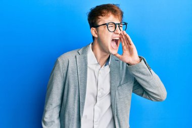 Zarif kıyafetler giymiş, gözlüklü genç beyaz bir adam bağırıyor ve ağızdan ağıza bağırıyor. iletişim konsepti. 