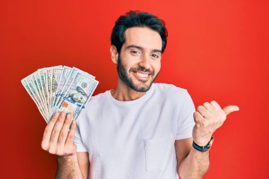 Hispanik genç adam dolarları tutuyor gururla bağırıyor, zaferi kutluyor ve başarıyı kollarını kaldırarak kutluyor. 