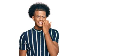 Afro saçlı, sıradan kıyafetler giyen, gergin ve elleri ağızda, tırnaklarını yiyormuş gibi görünen Afro-Amerikan bir adam. anksiyete. 