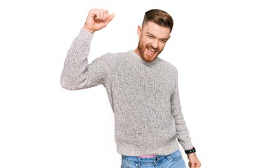 Genç kızıl saçlı sıradan bir kazak giyen mutlu ve neşeli dans eden, hareketli ve kendinden emin müzik dinleyen genç bir adam. 