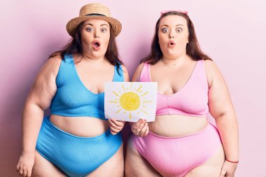 Bikini giyen genç ve cüsseli ikizler korku ve şaşkınlık içinde, ağzı açık, inançsız bir yüz ifadesi takınıyorlar. 