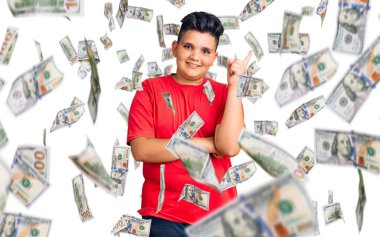 Günlük kıyafetler giyen küçük çocuk gülümseyerek mutlu bir şekilde elini ve parmağını kenarda gezdiriyor.