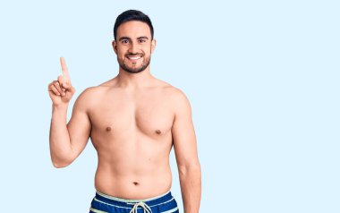 Mayo giyen genç yakışıklı bir numarayı gösterip işaret ederken kendinden emin ve mutlu gülümsüyor.. 