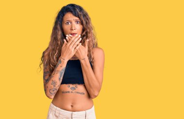 Günlük giysiler giyen Latin kökenli genç bir kadın yanlışlıkla elleri ile ağzını kapatırken şok oldu. gizli kavram. 