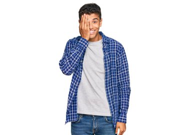 Genç, yakışıklı, Afro-Amerikalı bir adam günlük kıyafetler giyiyor. Bir gözünü eliyle kapatıyor. Yüzünde kendine güvenen bir gülümseme ve sürpriz bir duygu var.. 