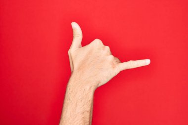 Kafkas genci parmaklarını izole edilmiş kırmızı arka planda gösteriyor Hawaii Shaka selamlama hareketi, telefon ve iletişim sembolü.