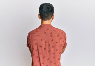 Yazlık kıyafetler giyen genç yakışıklı adam arkasını dönüp kollarını kavuşturarak başka tarafa bakıyor. 