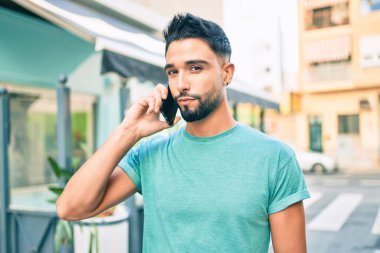 Şehirdeki akıllı telefondan konuşan, ciddi bir suratı olan genç bir Arap..