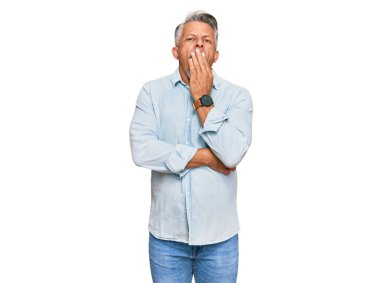 Orta yaşlı, gri saçlı, günlük kıyafetler giyen, esnemekten sıkılmış, ağzı eliyle kapatan bir adam. Huzursuz ve uykulu.. 