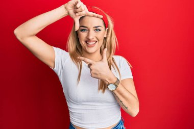 Gündelik beyaz tişört giyen, gülümseyen, elleri ve parmakları gülen yüzlü beyaz bir kadın. yaratıcılık ve fotoğrafçılık kavramı. 