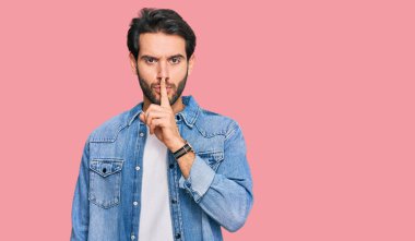 Gündelik kıyafetler giyen genç İspanyol adam parmakları dudaklarında sessiz olmak istiyor. sessizlik ve gizli konsept. 