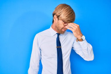 İş kıyafetleri ve gözlük takan genç sarışın yorgun burnu ve gözleri ovuşturup yorgun ve baş ağrısı çekiyor. Stres ve hüsran kavramı. 