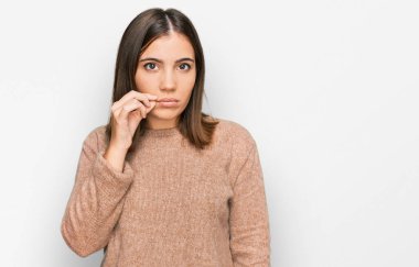 Gündelik kıyafetler giyen genç ve güzel bir kadın ağzı ve dudakları parmaklarıyla kapanan bir fermuar gibi. gizli ve sessiz, tabu konuşması 