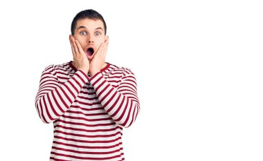 Çizgili kazak giyen genç yakışıklı adam korkmuş ve şok olmuş, şaşırmış ve şaşırmış bir yüz ifadesi var. 