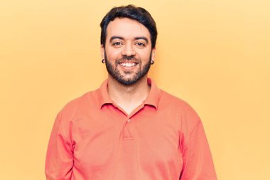 Yüzünde mutlu ve havalı bir gülümseme olan sıradan kıyafetler giyen genç İspanyol bir adam. şanslı kişi. 