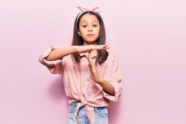 Gündelik kıyafetler giyen güzel bir kız çocuğu. El kol hareketleri yapıyor, hayal kırıklığına uğramış ve ciddi bir yüz ifadesi takınıyor. 