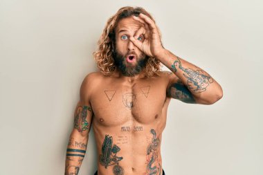 Sakallı, uzun saçlı, gömleksiz, güzel jest yapan, şaşırmış yüzüyle parmaklarından bakan yakışıklı bir adam. İnançsız ifade. 