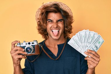 Klasik fotoğraf makinesi ve dolar tutan genç İspanyol adam komik bir ifadeyle mutlu bir şekilde dilini dışarı çıkarıyor.. 