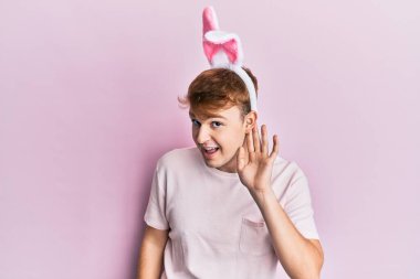 Paskalya tavşanı kulakları takan, ağzı kulaklarında gülümseyen, dedikodu ve dedikoduları dinleyen genç beyaz bir adam. Sağırlık kavramı. 