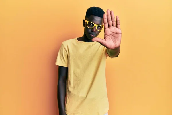 若いアフリカ系アメリカ人の男性がカジュアルな服を着て 眼鏡を手の手のひらで歌うのを止める 顔に負の重大なジェスチャーで — ストック写真
