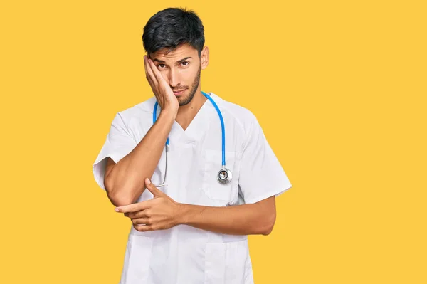 Jovem Homem Bonito Vestindo Uniforme Médico Estetoscópio Pensando Que Parece — Fotografia de Stock