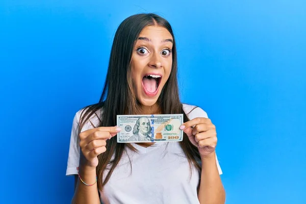 Młoda Latynoska Kobieta Banknotem 100 Dolarów Świętująca Szaleństwo Zdumiona Sukcesem — Zdjęcie stockowe