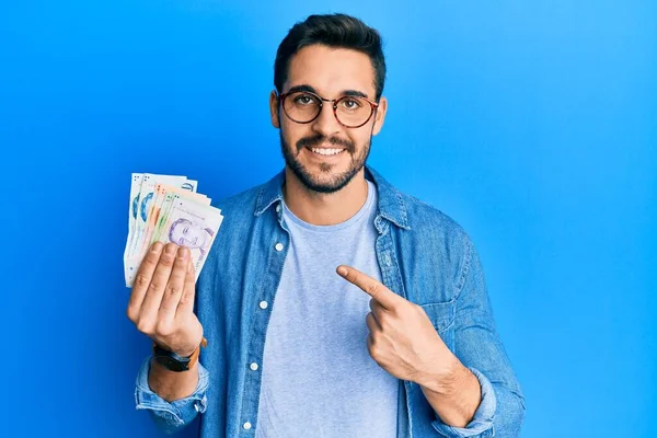 Jovem Hispânico Segurando Notas Dólares Singapore Sorrindo Feliz Apontando Com — Fotografia de Stock