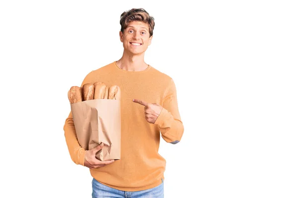 Νεαρός Όμορφος Άντρας Κρατά Χάρτινη Σακούλα Ψωμί Χαμογελώντας Χαρούμενος Δείχνοντας — Φωτογραφία Αρχείου