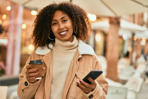 アフリカ系アメリカ人の若い女性が市内でスマートフォンやコーヒーを飲んでいる — ストック写真