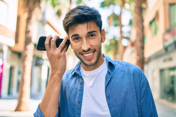 若いラテン人の笑顔幸せなリスニング音声メッセージを使用してスマートフォンで市内 — ストック写真