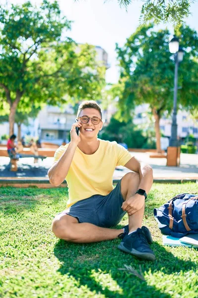 Молодой Латиноамериканец Улыбается Счастливо Используя Смартфон Сидя Траве Университетском Городке — стоковое фото