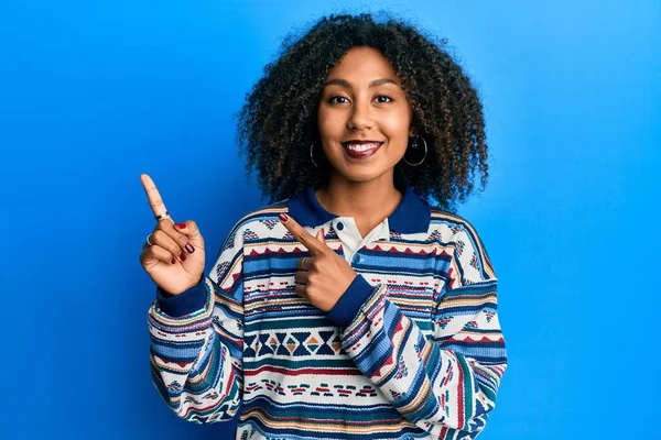 カジュアルな服を着てアフロの髪を持つ美しいアフリカ系アメリカ人女性は笑顔とカメラを見て2本の手と指で側面を指して — ストック写真