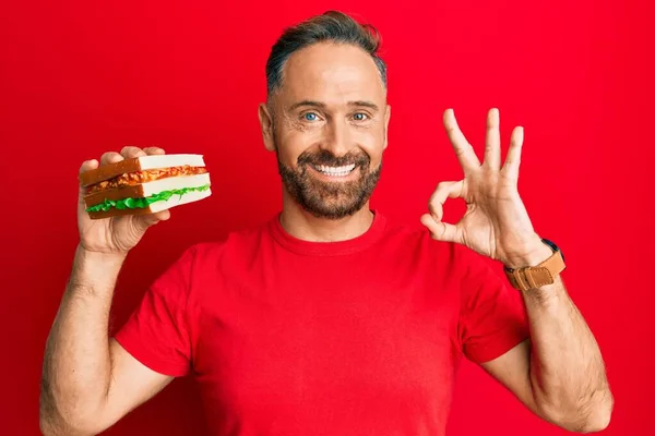 Bonito Homem Meia Idade Comendo Sanduíche Fazendo Sinal Com Dedos — Fotografia de Stock