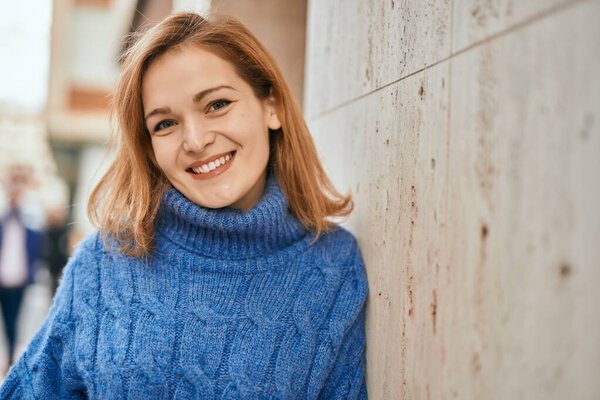 Молодая кавказская девушка улыбается счастливо стоя в городе.