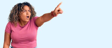 Genç Afro-Amerikan artı cüsseli kadın gündelik giysiler giyip parmağıyla işaret ederek şaşırdı, ağzı açık hayrete düştü, ön tarafta bir şey vardı. 