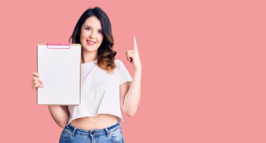 Güzel, genç, esmer bir kadın elinde boş alanı olan bir pano tutarken bir fikre ya da soru işaretine şaşırır. 