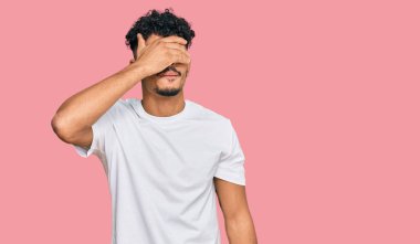 Genç Arap adam, sıradan beyaz tişörtler giyip gözlerini kapamış, ciddi ve üzgün görünüyor. Görme, saklama ve reddetme konsepti 