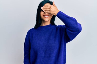 Gündelik giysiler giymiş genç beyaz bir kadın. Gülümsüyor ve elleri yüzüne gülüyor. Şaşırtmak için gözleri örtüyor. kör kavram. 