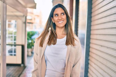 Genç beyaz kadın gülümseyerek şehirde mutlu mesut yürüyor..