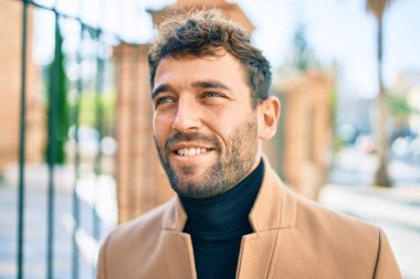 Zarif ceket giyen yakışıklı iş adamı dışarıda mutlu bir şekilde gülümsüyor.