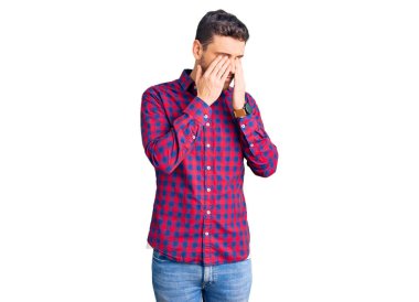 Ayılı yakışıklı genç bir adam. Günlük gömlek giyiyor. Yorgunluk ve baş ağrısı için gözlerini ovuşturuyor. görme sorunu 