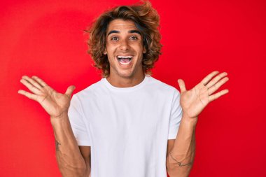 Gündelik beyaz tişört giyen genç İspanyol adam zaferi mutlu bir gülümsemeyle ve kazanan yüz ifadesiyle kutluyor. 