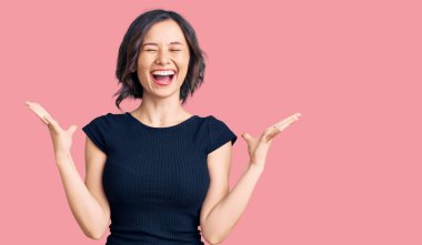 Gündelik giysiler giyen genç ve güzel bir kız başarı için deli ve çılgınlığı kutluyor kollarını kaldırmış ve gözlerini kapatmış heyecanla bağırıyor. Kazanan konsept 