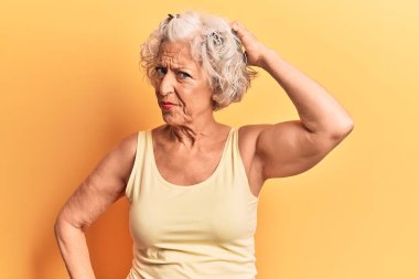 Üstün gri saçlı, günlük kıyafetler giyen bir kadın soru sorup kafasını karıştırıyor. Şüpheyle kararsız, kafa kafaya düşünerek. Düşünceli kavram. 