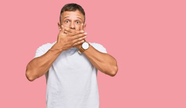 Beyaz tişört giyen yakışıklı kaslı adam yanlışlıkla elleri ile ağzını kapatırken şok oldu. gizli kavram. 